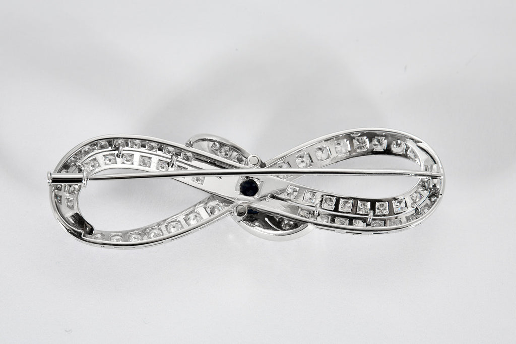 Broche Infini en platine, diamants et centre saphir.
