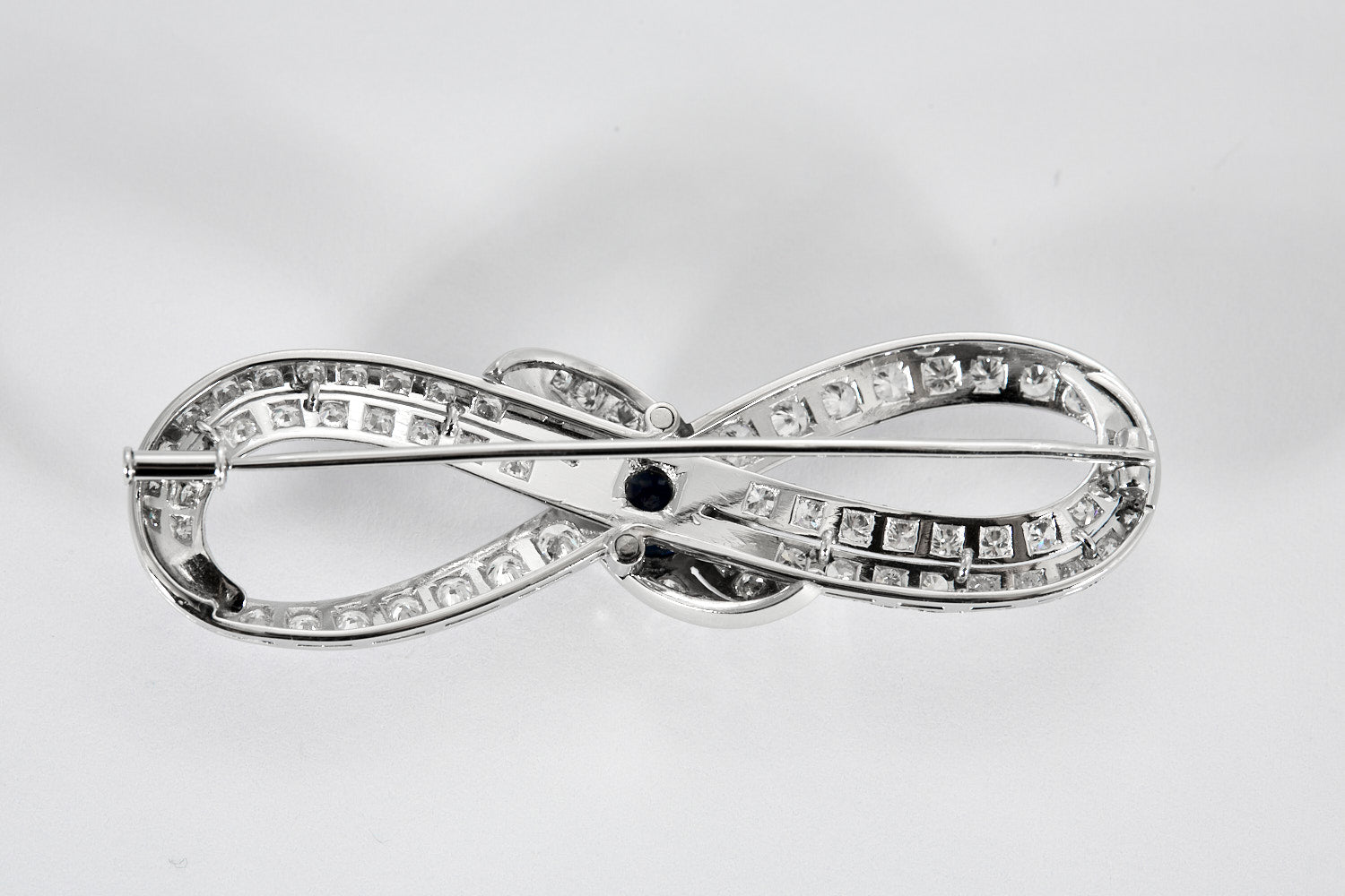 Broche Infini en platine, diamants et centre saphir.